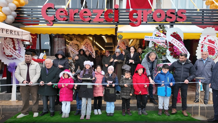 Çocuklar ve yetişkinler, Çerezci Gross Market'in açılışında kurdele kesmek için sırada duruyor.