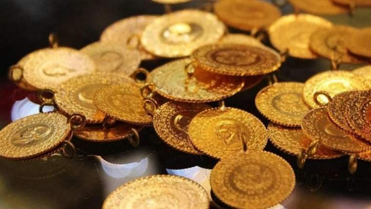 Çeşitli boyutlarda, sarı ve bakır tonlarındaki madeni paralar parlak bir yüzey üzerinde üst üste duruyor.