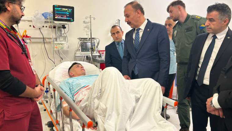 Hastanede yatan bir asker, yanında doktor ve ziyaretçilerle birlikte yatakta uzanıyor.