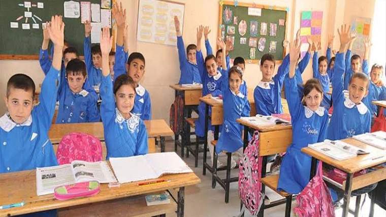 Sınıfta oturan öğrenciler, ellerini kaldırmış şekilde ders dinliyorlar.