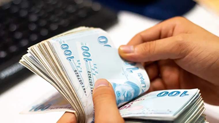 Bir kişinin elinde 100 TL banknotlardan oluşan bir deste para tutuluyor.