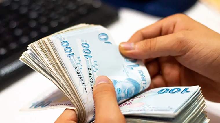 Bir kişinin elinde 100 TL banknotlardan oluşan bir deste para tutuluyor.