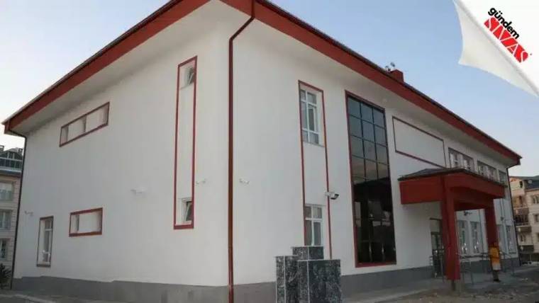 Yeni eğitim yılına hazırlanan beyaz bir okul binası, önünde taş sütunlar var.