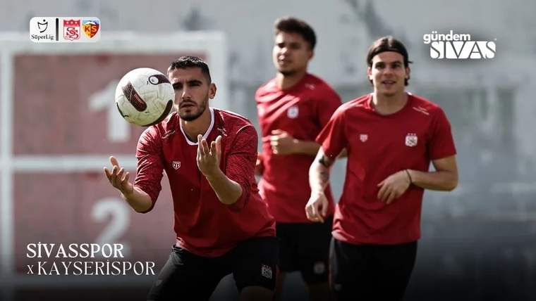 Kırmızı forma giymiş futbolcular, antrenman sırasında topu havada tutmaya çalışıyor.