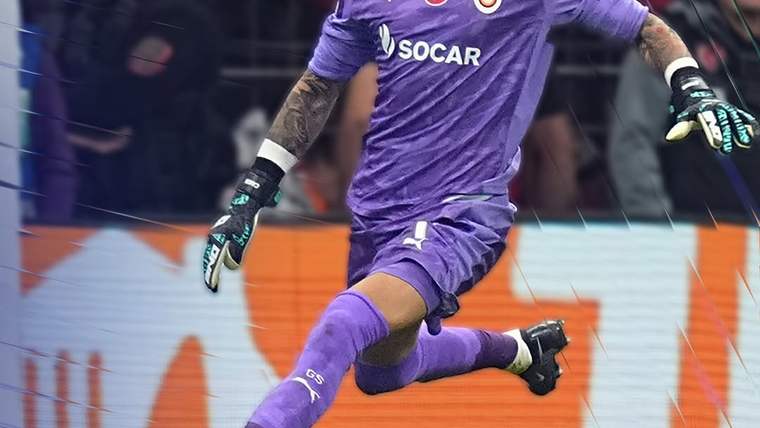 Mor kaleci forması giymiş bir futbolcu, kaleye doğru koşuyor.