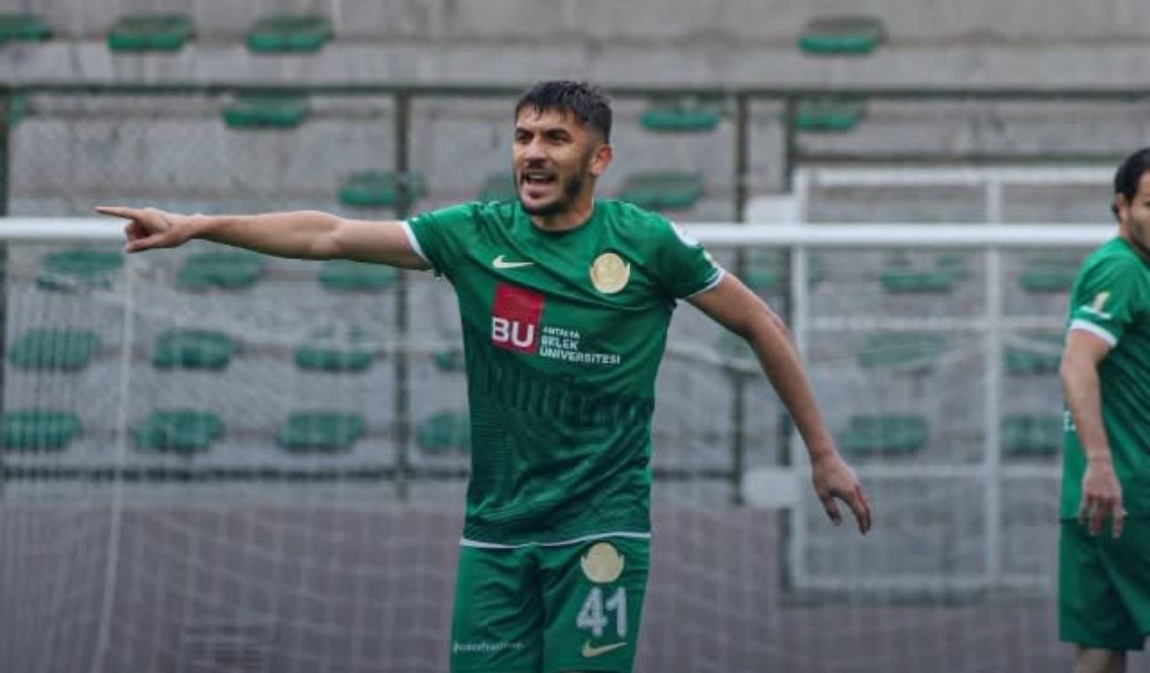 Yeşil forma giymiş bir futbolcu, sahada işaret ederek bir şeyler anlatıyor.