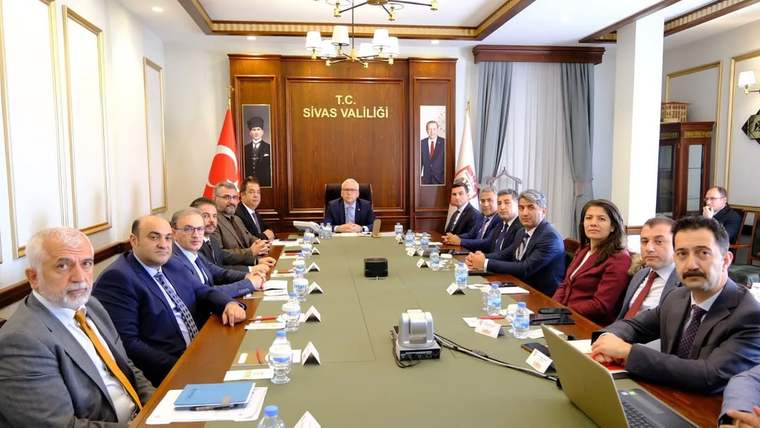 Sivas Valiliği yazılı salonda, uzun toplantı masası çevresinde oturan bir grup kişi görülüyor.