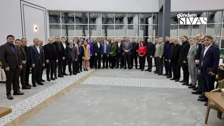 Bir grup insan, iç mekanında bir araya gelerek poz veriyor.