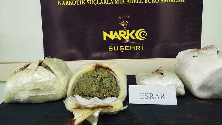 Üzerinde Sivas Valiliği ve Emniyet Müdürlüğü yazan panonun önünde paketler, açık pakette yeşil madde ve “ESRAR” etiketi bulunuyor.