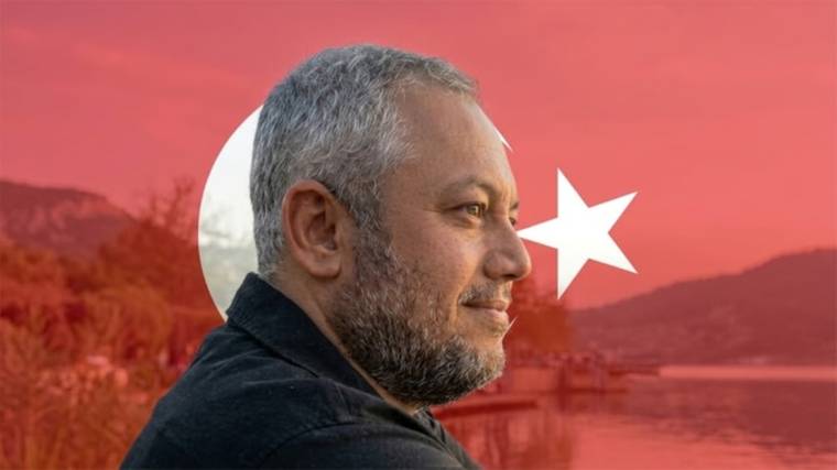 Gri saçlı ve sakallı bir adamın profili, arka planda ay yıldızlı kırmızı bayrak ve dağ manzarası.