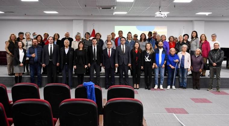 Bir salonda, sıralar halinde duran kadın ve erkeklerden oluşan kalabalık bir grup poz veriyor.