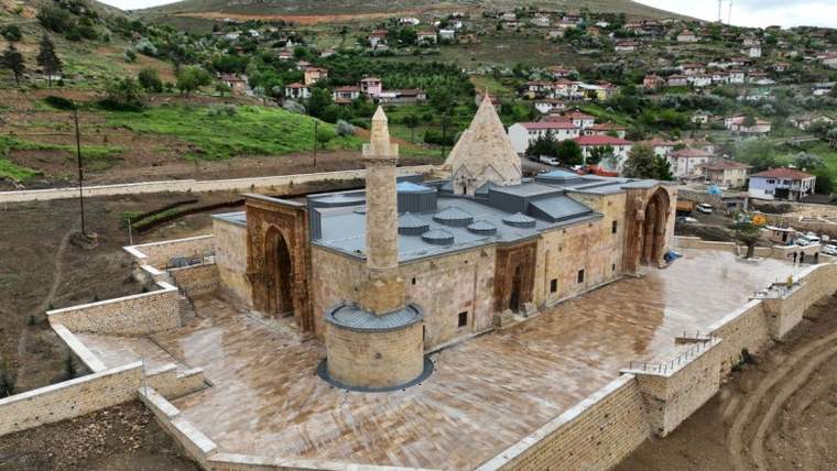 Divriği Ulu Camii'nin dış görünümü, çevresinde yeşil alanlar ve evler yer alıyor.