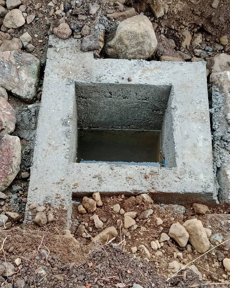 Beton bir yapıda su birikintisi, etrafında taşlar ve toprak görünmekte.