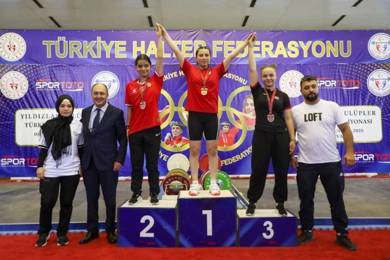 Halter podyumunda üç sporcu madalyalarıyla duruyor; çevrelerinde dört kişi, arkada Türkiye Halter Federasyonu pankartı var.