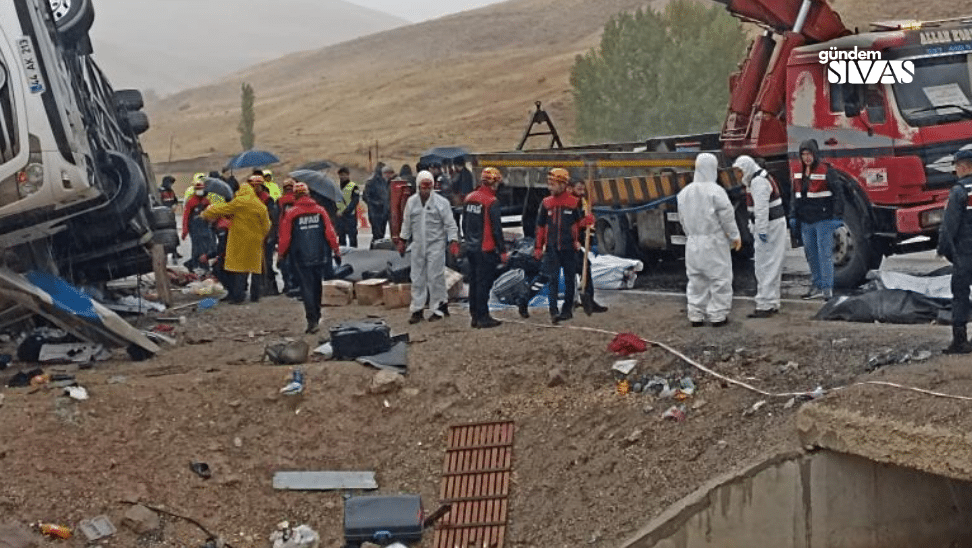 Kaza alanında, kurtarma ekipleri ve sağlık görevlileri çalışıyor, devrilmiş bir otobüs görünmekte.