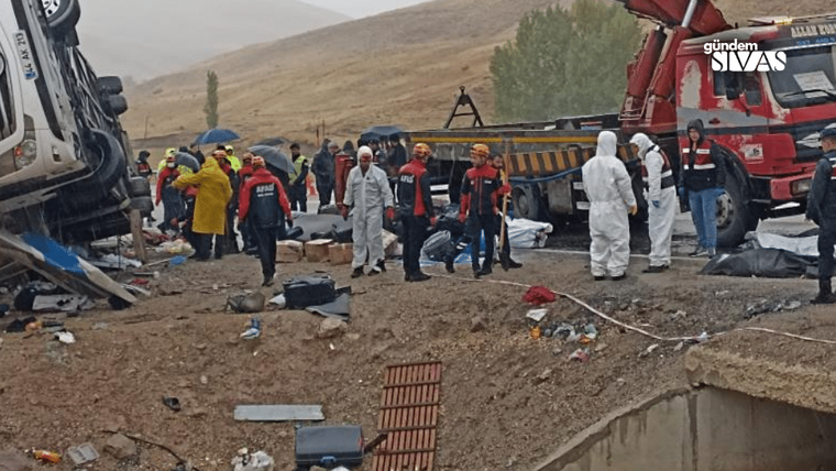 Kaza alanında, kurtarma ekipleri ve sağlık görevlileri çalışıyor, devrilmiş bir otobüs görünmekte.