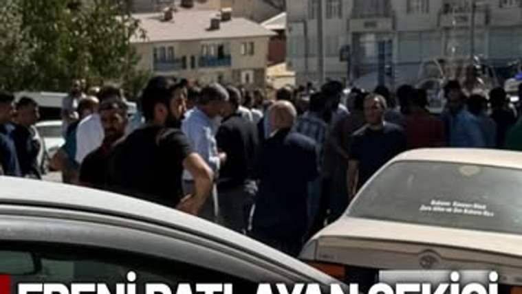 Sokakta park etmiş araçların yanında toplanan kalabalık ve önde görünen iki otomobil yer alıyor.