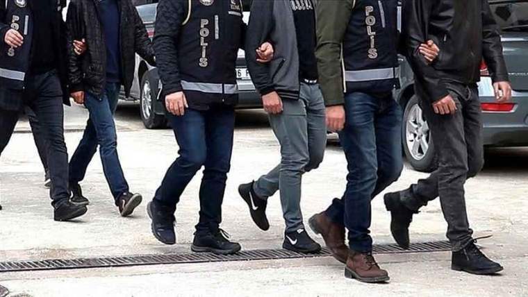 Polis ekipleri, gözaltına alınan kişileri götürüyor. Yerdeki ızgara ve araçlar görünmekte.