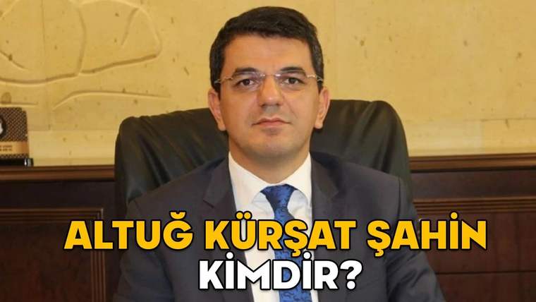 Bir kişi, ofisinde otururken kameraya bakıyor. Arka planda açık renkli bir duvar var.
