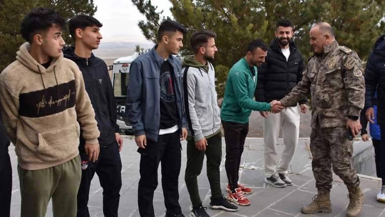 Kars 36 Spor Tesisleri'nde, bir grup gençle selamlaşan bir kişi, askeri kıyafet giymekte.