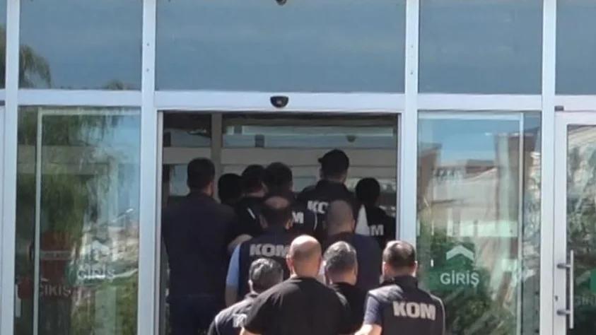 KOM yazılı üniformalar giymiş bir grup, bir binanın giriş kapısından içeri giriyor.