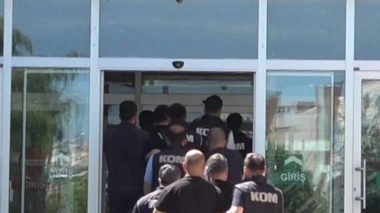 KOM yazılı üniformalar giymiş bir grup, bir binanın giriş kapısından içeri giriyor.