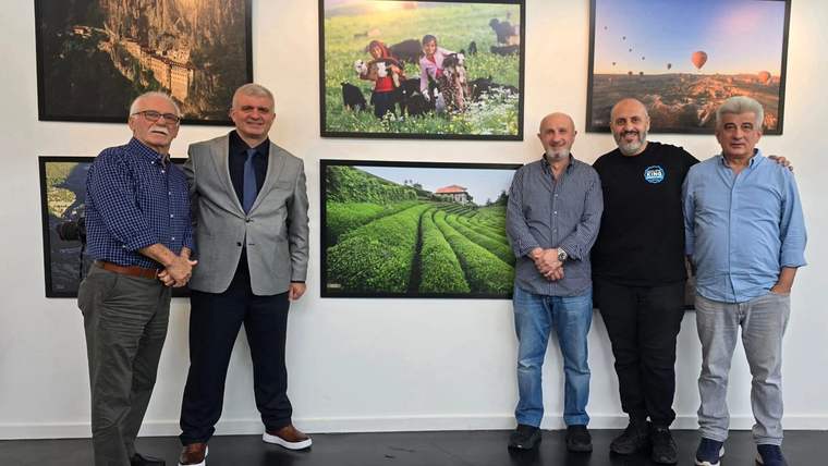 Sergi salonunda beş erkek, duvarlarda asılı doğa ve kültür temalı fotoğrafların önünde yan yana duruyor.