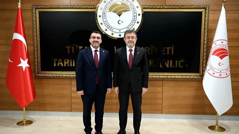 Tarım Bakanlığı'nın önünde, iki kişi yan yana duruyor. Arkada Türkiye Cumhuriyeti arması ve bayraklar var.