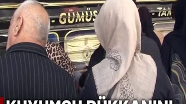 Kuyumcu vitrini önünde, aralarında başörtülü bir kadının da bulunduğu birkaç kişi görülüyor.