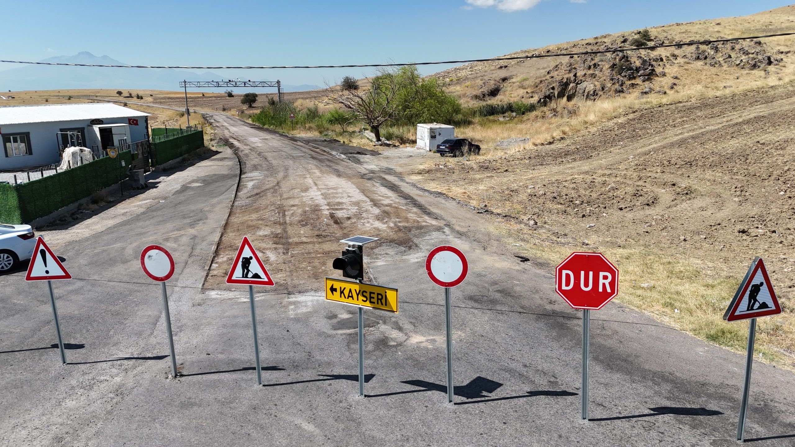 Yolda çeşitli trafik uyarı levhaları ve dur işareti bulunuyor, yol çalışması için kapatılmış.