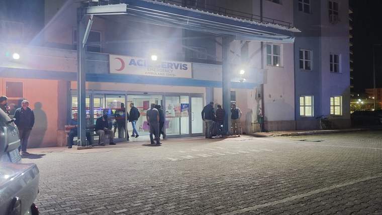 Hastane acil servisinin önünde bekleyen bir grup insan, gece saatleri.