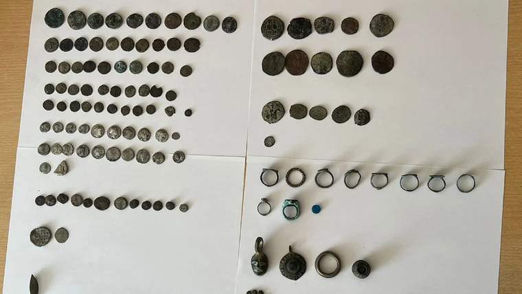 Beyaz zemin üzerinde düzenli bir şekilde yerleştirilmiş çeşitli metal paralar ve takı parçaları.