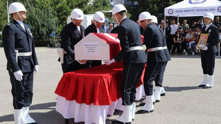 Beyaz miğferli ve tören üniformalı görevliler, Türk bayrağına sarılı tabutu taşırken görülüyor.