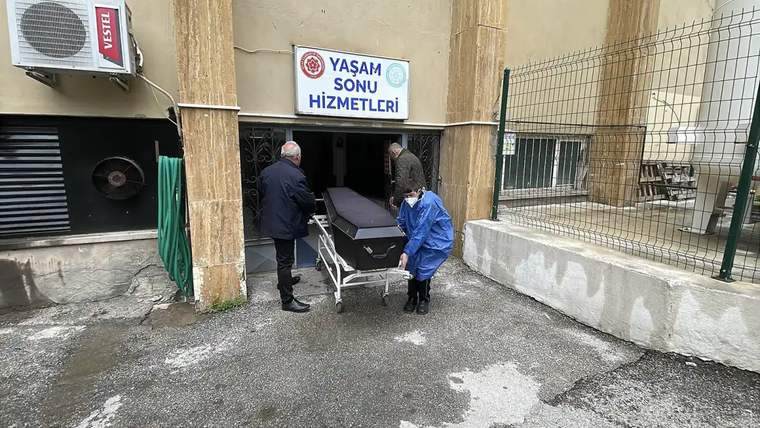 Bir cenaze aracı, morgdan çıkarılan bir tabutla birlikte taşınıyor.