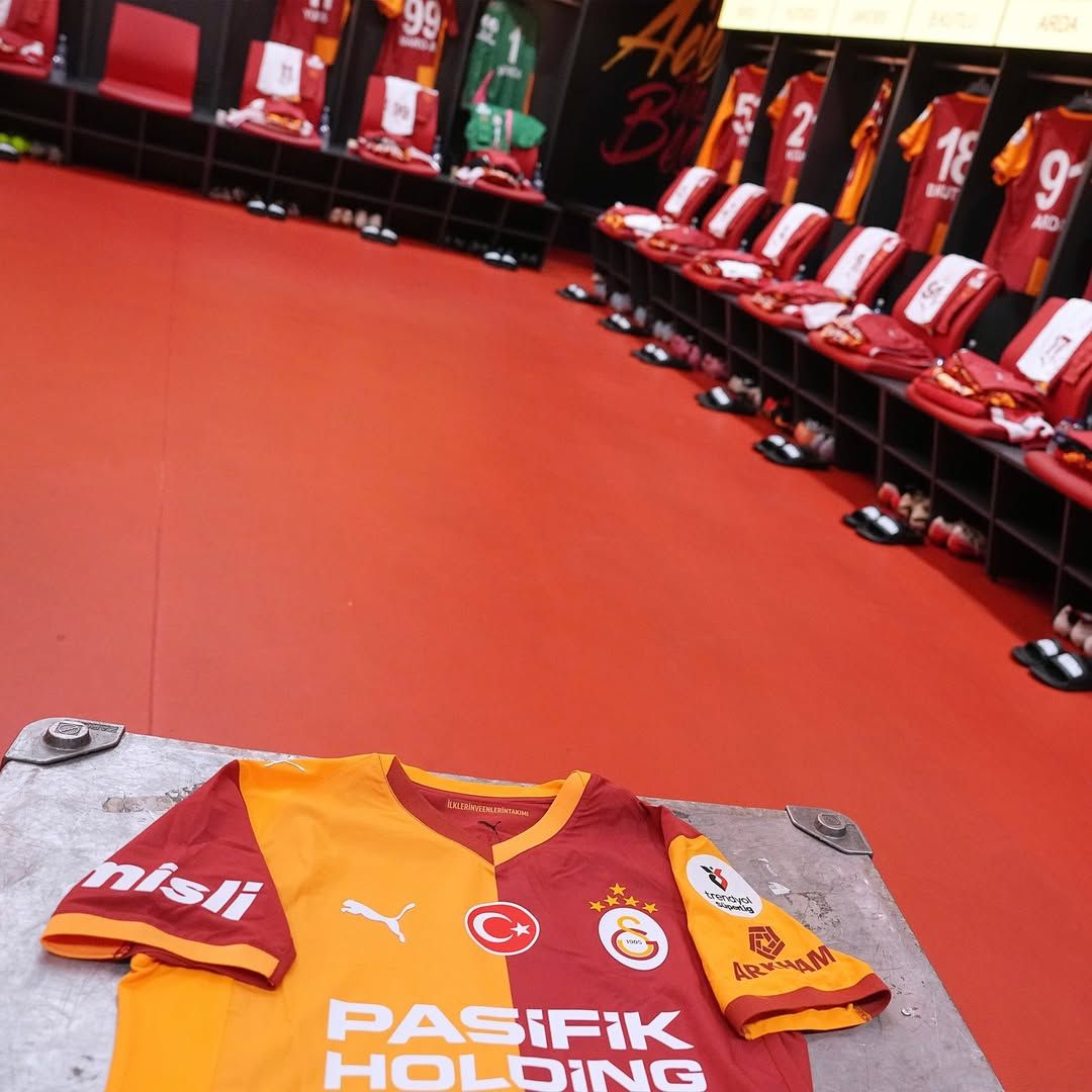 Galatasaray soyunma odasında, yerde bir forma ve sıralı koltuklar yer alıyor.