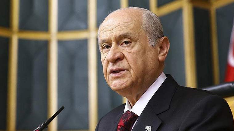Kürsüde konuşan bir kişi, arka planda ahşap paneller var.