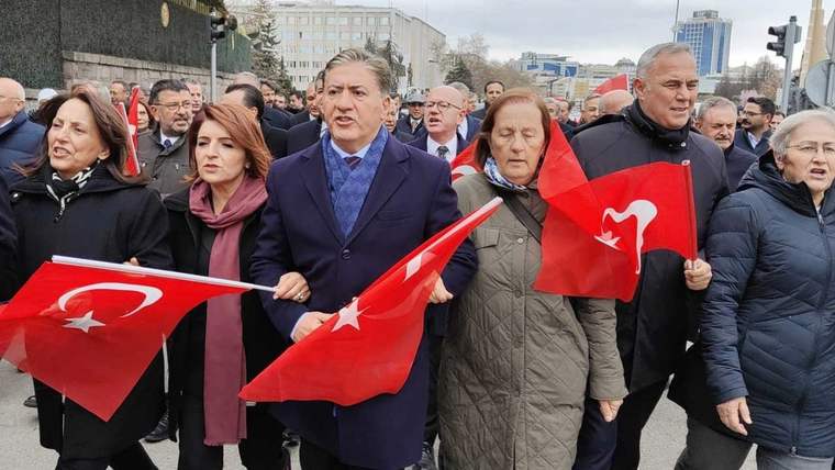 Türk bayrağı taşıyan kalabalık, yürüyüş yaparak bir yolda ilerliyor.