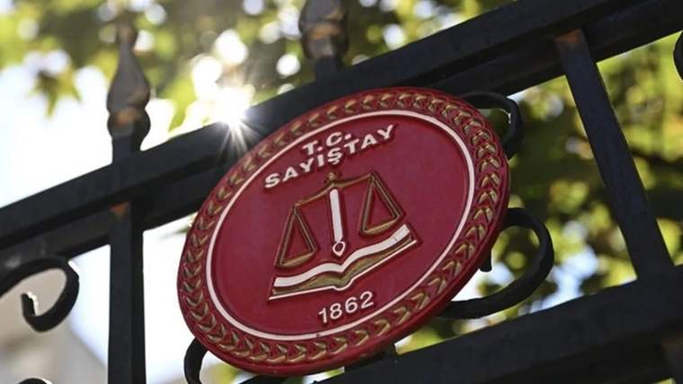 Siyah demir parmaklığa asılı, üzerinde “T.C. SAYIŞTAY” yazan kırmızı oval amblem görülüyor.