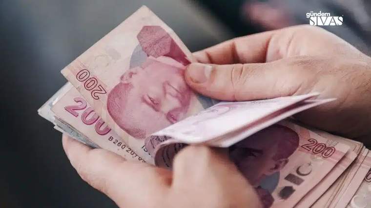 Bir kişinin elinde 200 TL banknotlar var, paralar katlanmış şekilde tutuluyor.