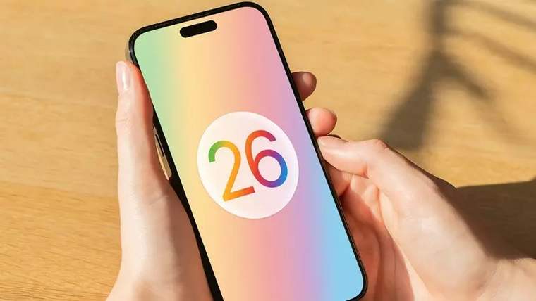 Elde tutulan akıllı telefonun ekranında renkli bir arka plan üzerinde “26” rakamı görülüyor.