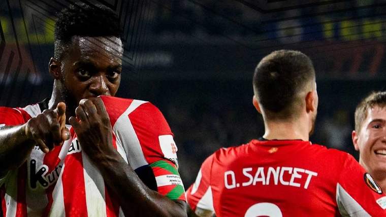 Futbolcular, bir maç sırasında forma giyerek sahada duruyorlar; biri formasını öpüyor.