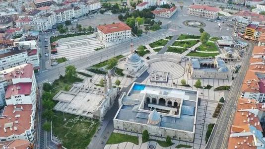 Sivas'ta bir meydan görünümü, çevresinde binalar ve yeşil alanlar var.