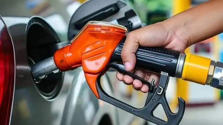 Turuncu yakıt tabancası, bir aracın yakıt deposu girişine yerleştirilmiş halde tutuluyor.