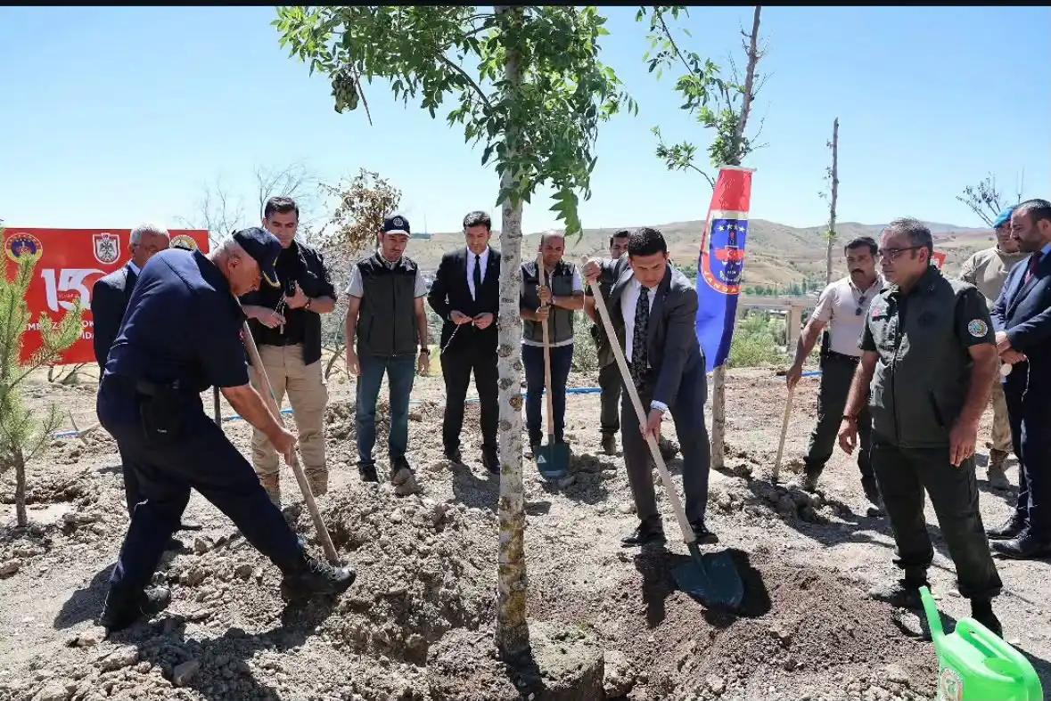 Ağaç dikimi etkinliğinde, katılımcılar ağaç dikerken ve çevrede bayraklar görünürken.