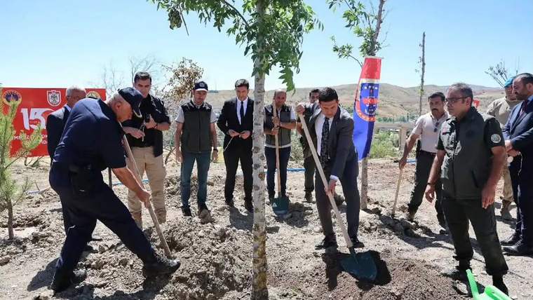 Ağaç dikimi etkinliğinde, katılımcılar ağaç dikerken ve çevrede bayraklar görünürken.