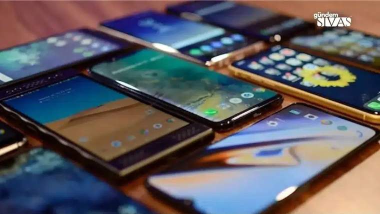 Farklı modellerde akıllı telefonlar, ekranları açık şekilde ahşap bir yüzey üzerinde yan yana duruyor.