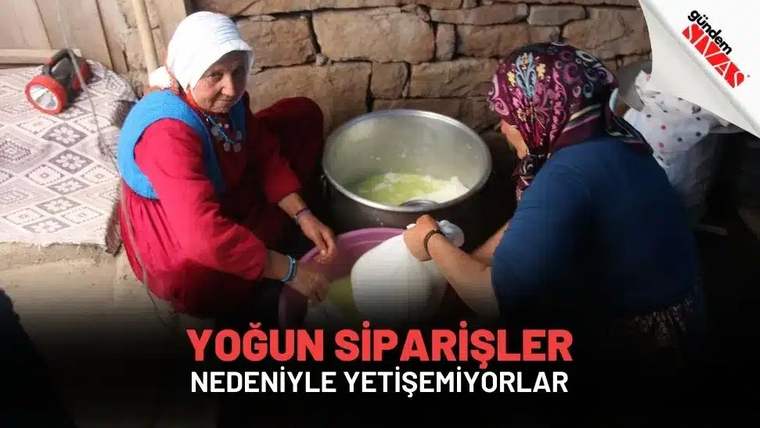 Taş duvarlı bir odada iki kadın, büyük metal kaptaki yiyeceğin yanında hazırlık yapıyor.