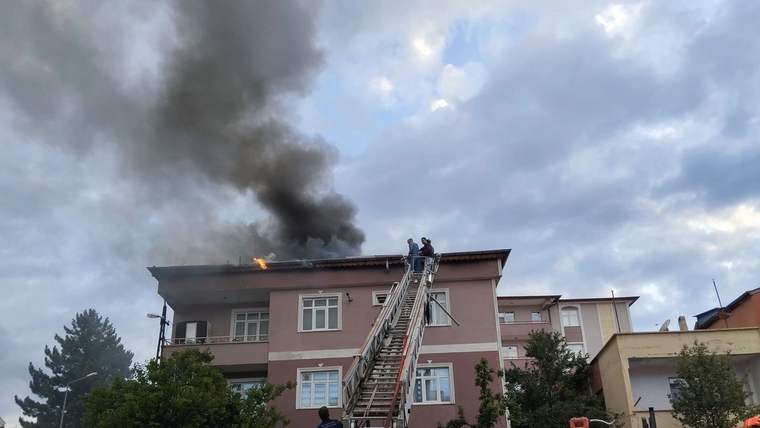 Suşehri Belediyesi itfaiye aracı, apartmanın çatısına uzanan merdiven ve yükselen siyah duman görülüyor.