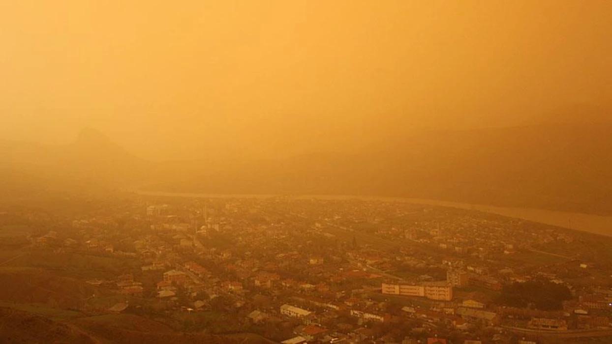 Hava, çöl tozu nedeniyle sarımsı bir renge bürünmüş, şehir manzarası bulanık görünüyor.