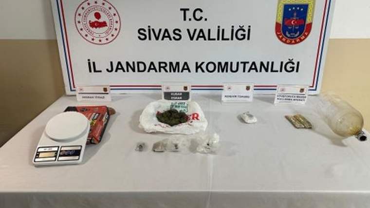 Sivas Valiliği İl Jandarma Komutanlığı yazılı pano önünde hassas terazi, poşetler ve çeşitli paketler bulunuyor.
